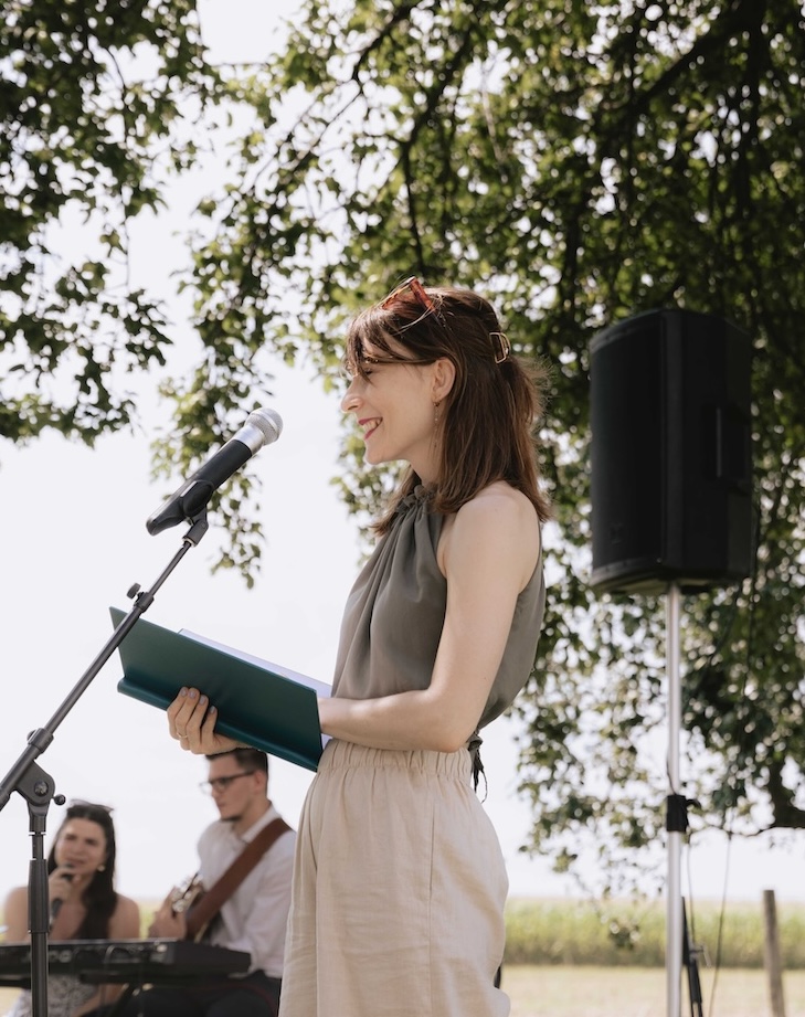 Eine junge Frau mit einer Mappe in der Hand steht vor einem Mikrofon